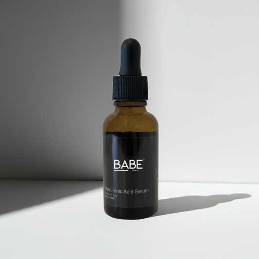 Bottle of Babe Hyaluronic Acid Serum with dropper on white surface and background